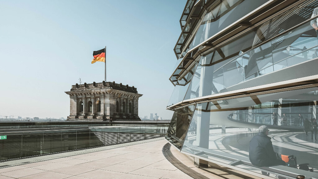 Sie sehen einen Teil der Glaskuppel und einen Turm des Reichstagsgebäudes in Berlin.