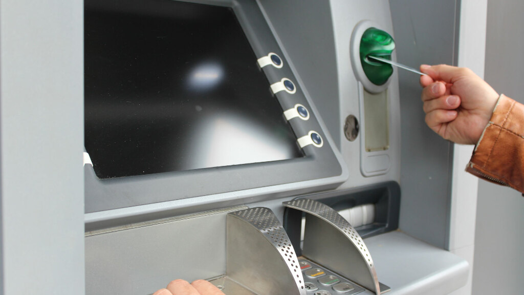 Sie sehen einen Geldautomaten, an dem gerade Geld abgeholt wird.