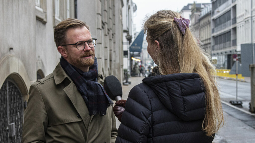 Sie sehen eine Reporterin, die einen Mann auf der Straße befragt.