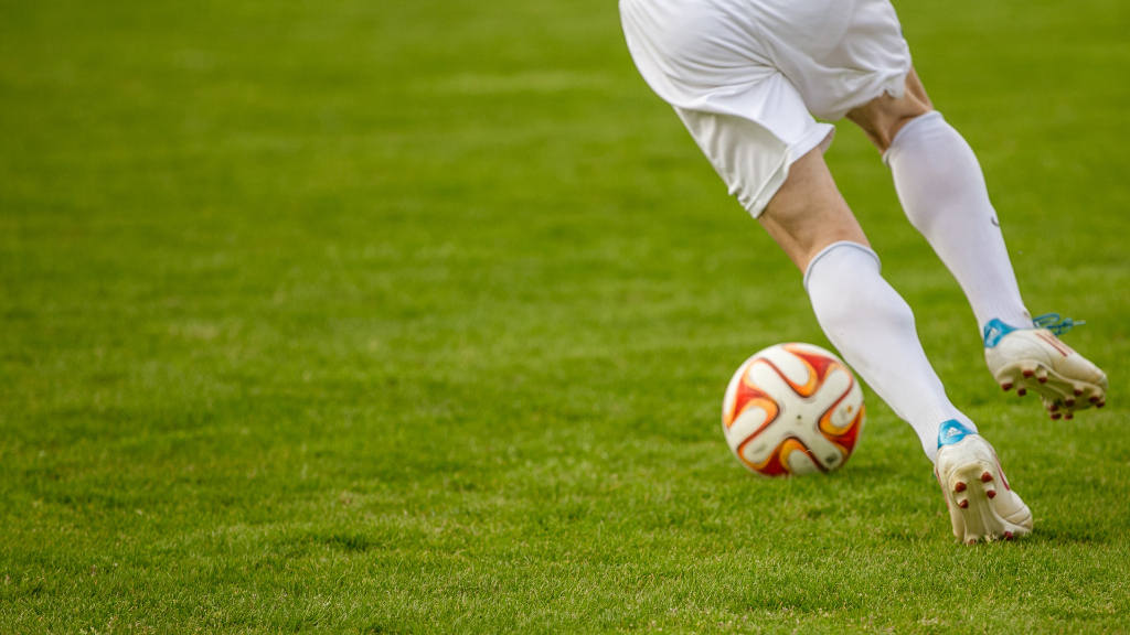 Sie sehen einen Fußballspieler auf dem Rasen.