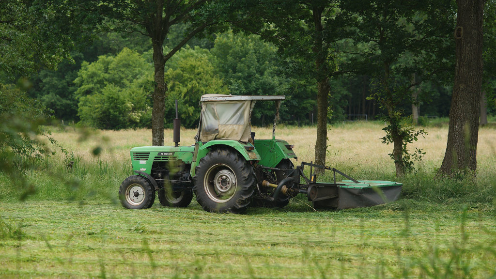 Sie sehen einen Traktor beim Mähen einer Wiese.