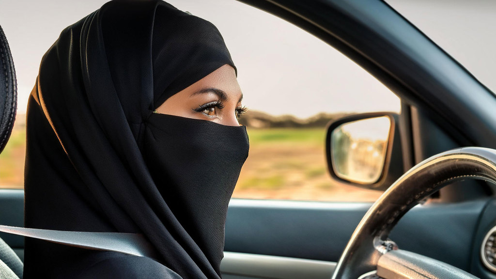 Sie sehen eine vollverschleierte Frau beim Autofahren.