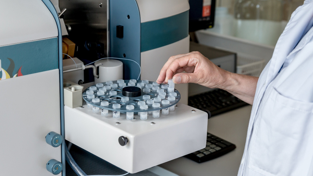 Sie sehen eine Apparatur, in welcher verschiedene Reagenzgläser stehen, in einem Labor.