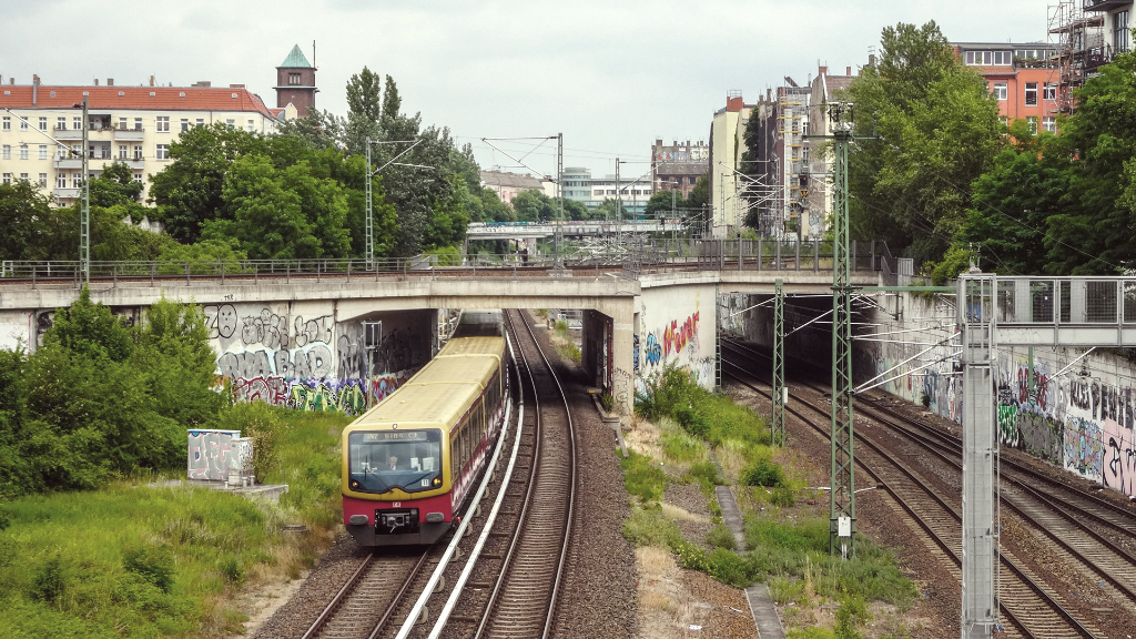 Sie sehen eine fahrende S-Bahn, wie sie gerade eine Brücke durchfährt.
