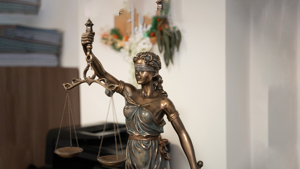 Sie sehen eine Bronzestatur der Justizia in einem Büro.