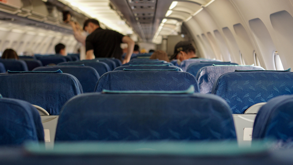 Sie sehen den Innenraum eines Linienflugzeugs und mehrere junge Männer darin.