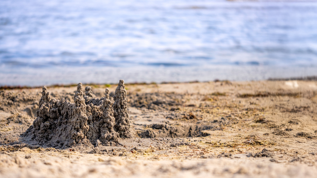 Sie sehen eine Sandburg an einem Strand.