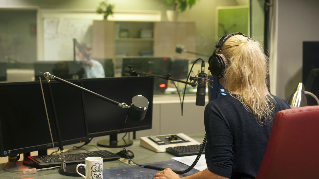 Sie sehen ein Radiostudio mit einer Moderatorin am Mikrofon.