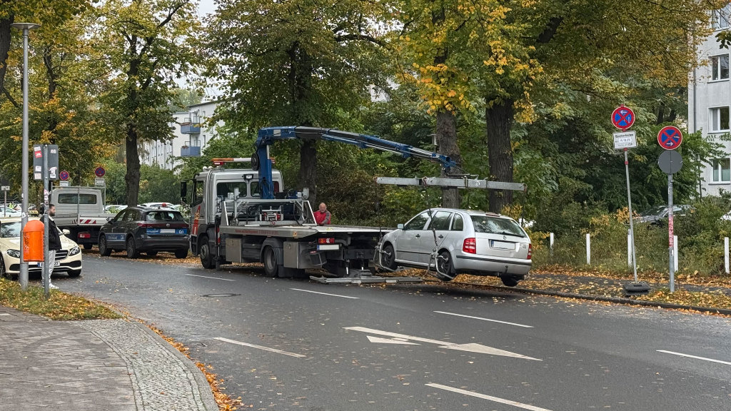 Sie sehen einen Abschleppwagen beim Aufladen eines PKWs.