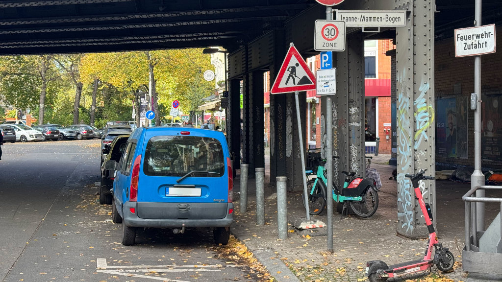 Sie sehen ein Baustellenschild in einer großstädtischen Nebenstraße, neben einem parkenden Auto