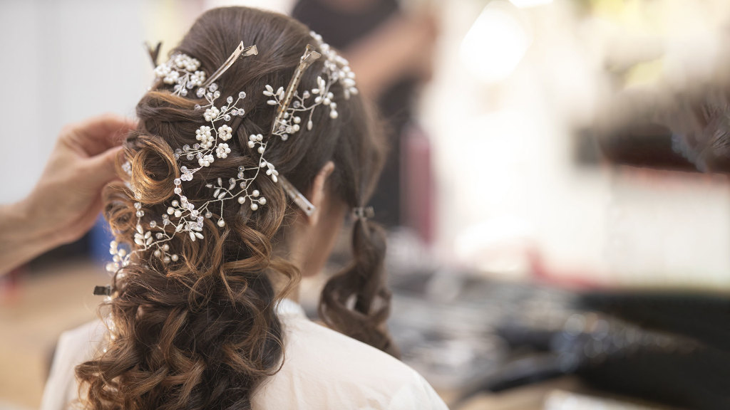 Sie sehen eine Braut, die sich die Haare frisieren lässt.