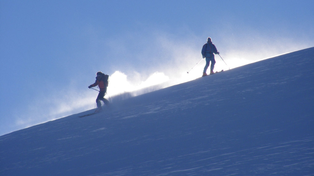 Sie sehen zwei Ski-Fahrer auf der Piste