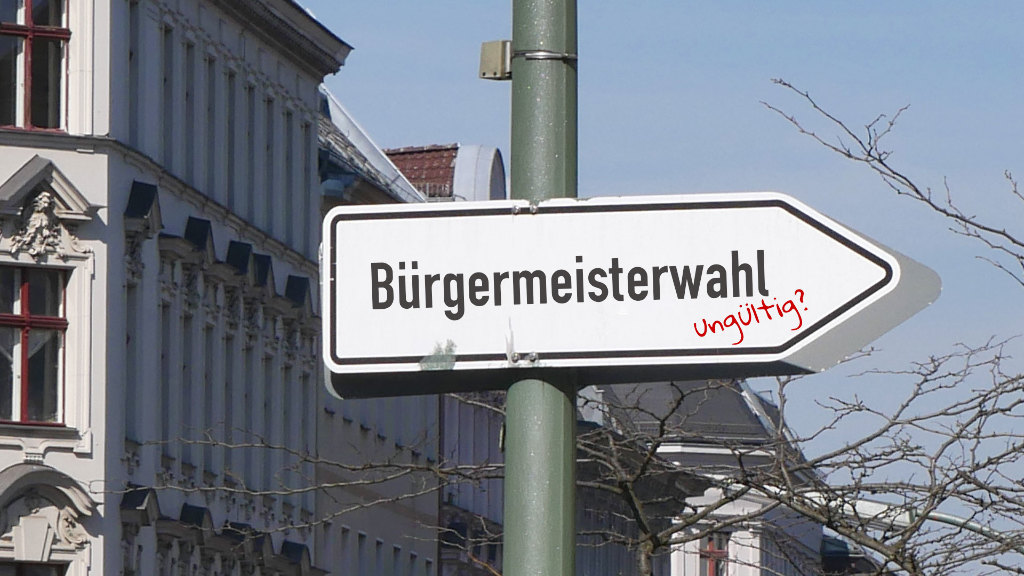 Sie sehen einen Wegweiser, der mit &bdquo;Bürgermeisterwahl&ldquo; und &bdquo;ungültig?&ldquo; beschriftet wurde.
