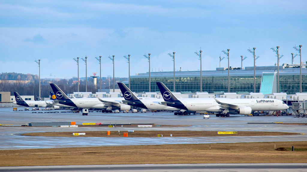 Sie sehen mehrere Flugzeuge der Lufthansa auf am Terminal eines Flughafens.