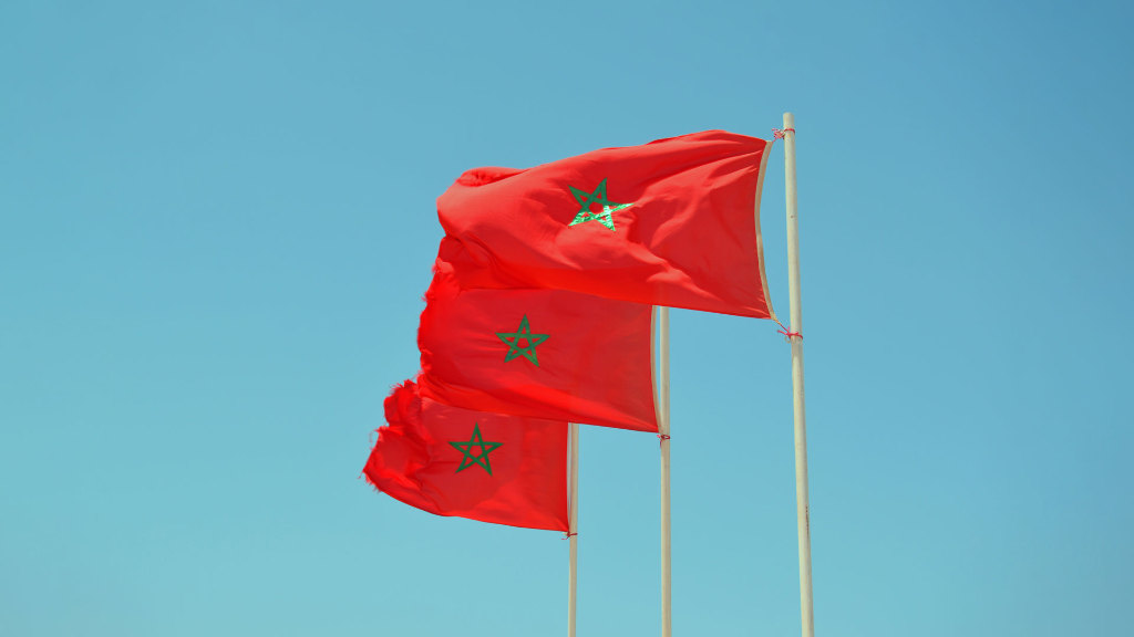 Sie sehen drei Fahnenmasten jeweils mit der Flagge des Konigreichs Marokko.