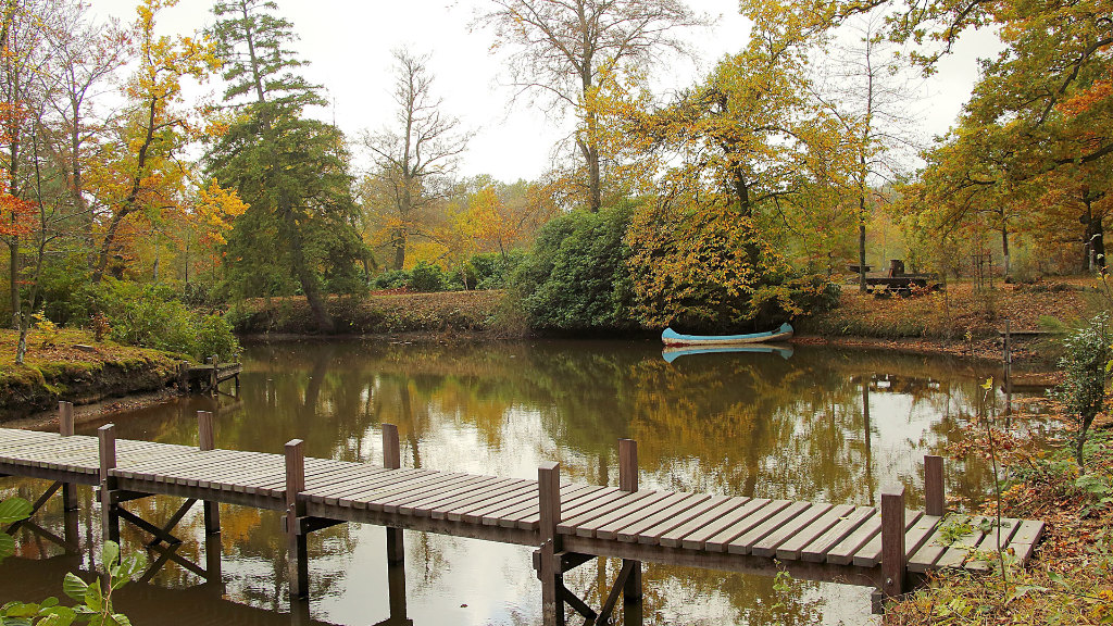 Sie sehen einen Teich mit einem Steg, auf dem ein Kanu schwimmt.
