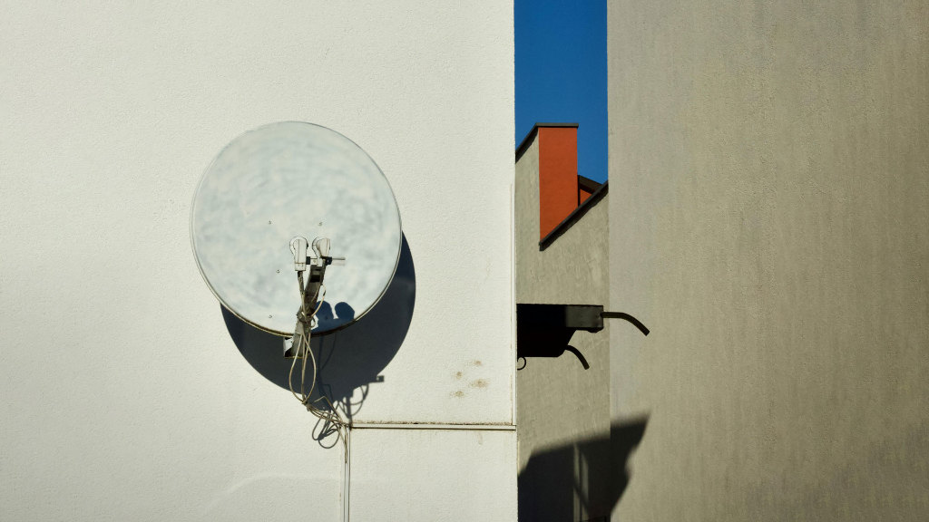 Sie sehen eine Satelittenschüssel an einer Häuserwand.