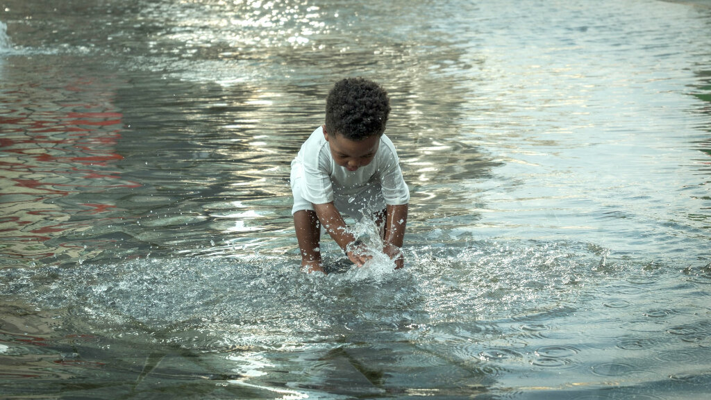 Sie sehen ein Kleinkind beim Planschen im Wasser.