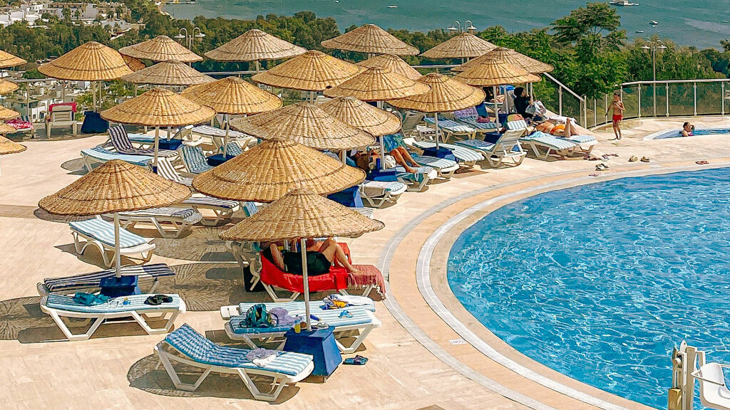 Sie sehen Strandliegen an einem Swimming-Pool in einem Ferienressort in der Türkei.