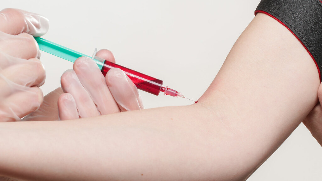 Sie sehen einen Arm von dem Blut abgenommen wird.