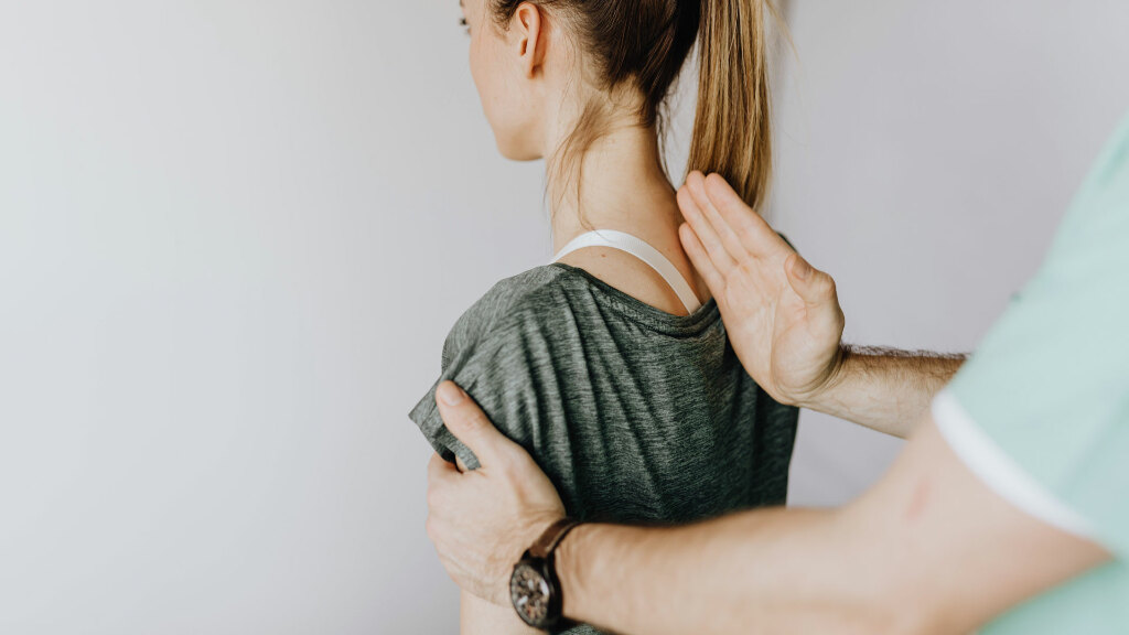 Sie sehen einen Chiropraktiker, der die Wirbelsäule einer Patientin ein und konzentriert sich auf Ausrichtung und Korrektur der Körperhaltung in einer klinischen Umgebung.