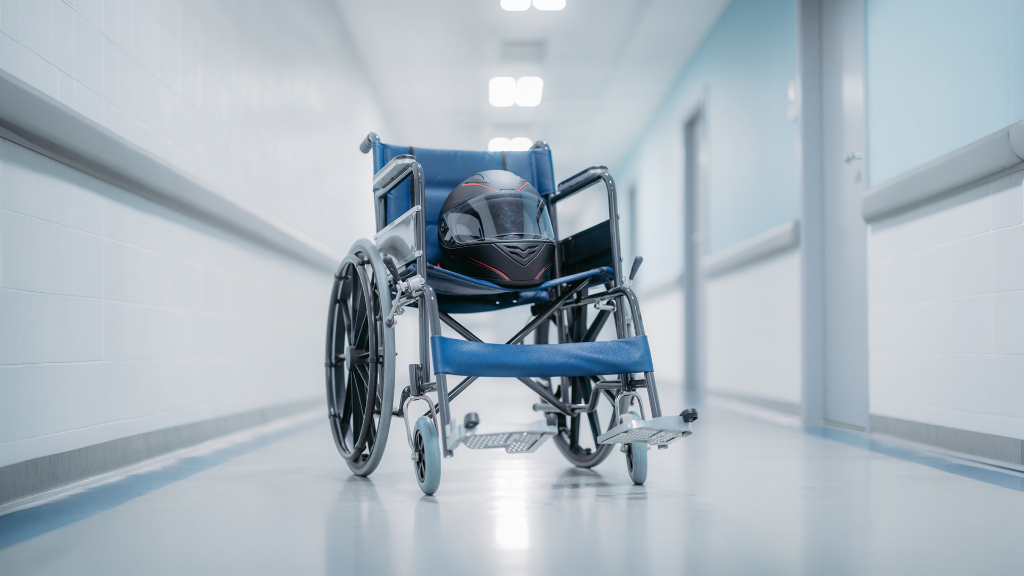 Sie sehen einen Rollstuhl in einem Krankenhausflur, auf dessen Sitzfläche ein Motorradhelm liegt.