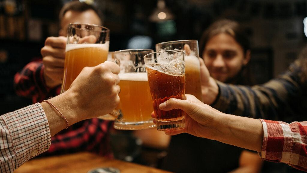 Sie sehen ein Gruppe von Freunden, die einen feierlicher Toast mit Bierkrügen aussprechen.