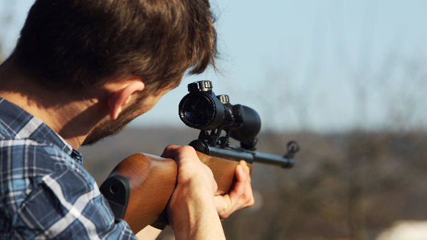 Sie sehen einen Mann mit einem Jagdgewehr im Anschlag.