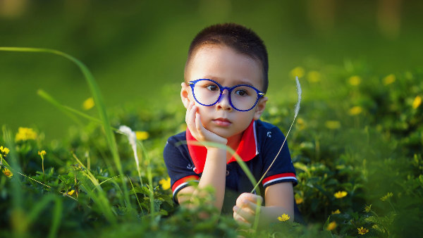 Sie sehen ein Kind mit Brille auf der Wiese.