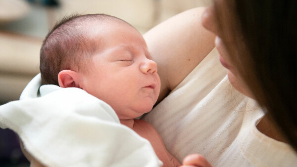 Sie sehen ein Baby im Arm einer Frau.