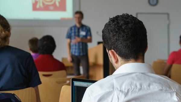 Sie sehen eine Gruppe von Personen in einem Seminar.