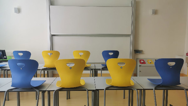 Sie sehen ein leeres Klassenzimmer mit Stühlen und Tischen.