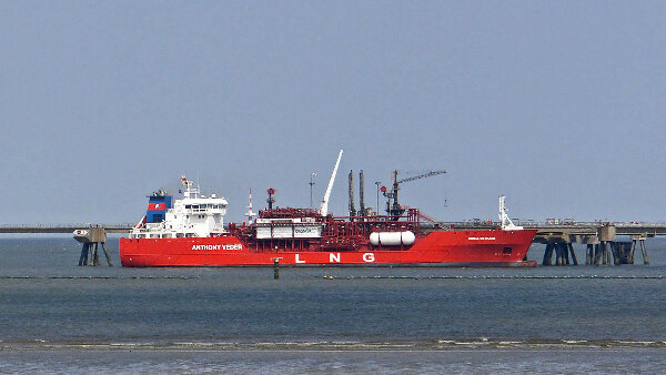 Sie sehen einen Flüssiggastanker, der an einem LNG-Terminal vor Anker liegt.