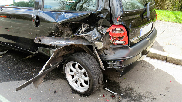 Sie sehen einen, bei einem Unfall, stark beschädigten Kleinwagen.