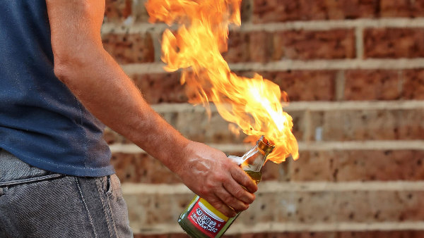 Sie sehen eine Person mit einem brennenden Molotow-Cocktail in der Hand.