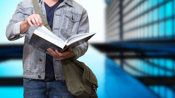 Sie sehen einen Studenten mit einem Buch in der Hand.