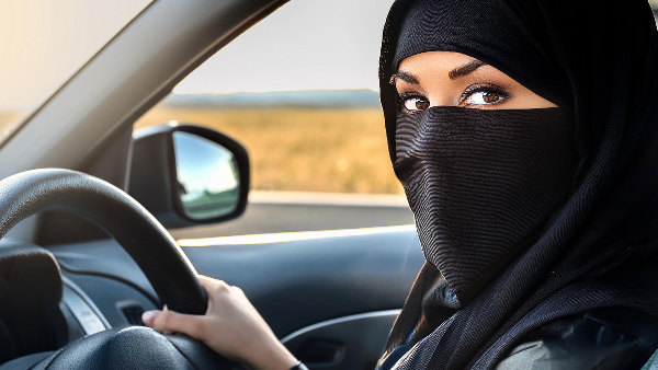 Sie sehen eine vollverschleierte Frau beim Autofahren.