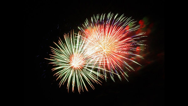 Sie sehen zwei Fontänen von explodierendem Feuerwerk am Nachthimmel.