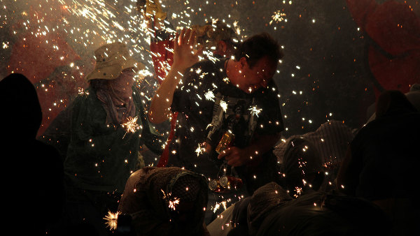 Sie sehen mehrere Leute in einem Funkenregen, der von Feuerwerk stammt.