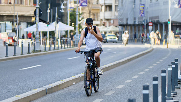 Sie sehen einen Radfahrer, der auf einer von der Fahrbahn abgetrennten „Protected Bike Lane“ fährt.