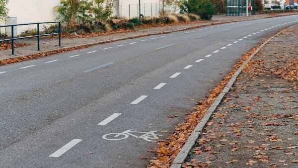 Sie sehen eine Straße in einem Ort, auf der ein Teil der Fahrbahn als Streifen für Radfahrer markiert wurde.