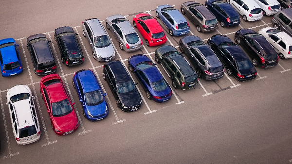 Sie sehen verschiedene Autos auf einem asphaltierten Parkplatz.