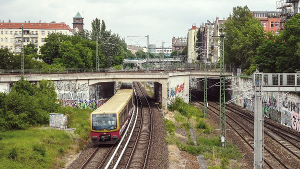 Sie sehen eine fahrende S-Bahn, wie sie gerade eine Brücke durchfährt.
