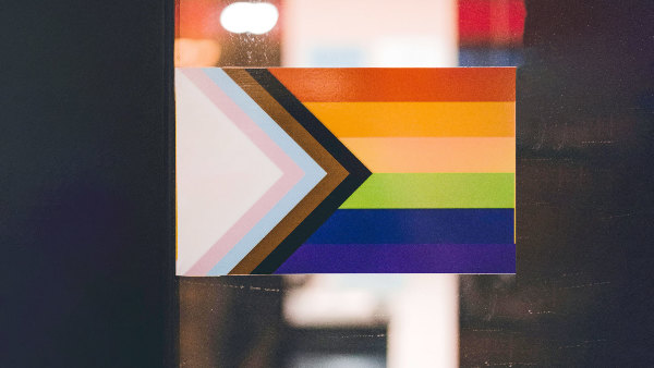 Sie sehen eine selbstgemachte „Progress-Pride“-Flagge, die an einer Tür klebt.