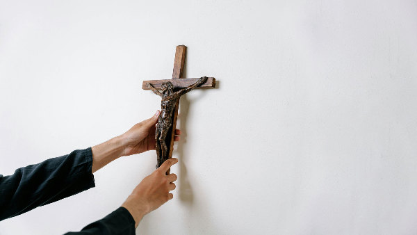 Sie sehen ein Kruzifix, wie es von der Wand abgenommen wird.