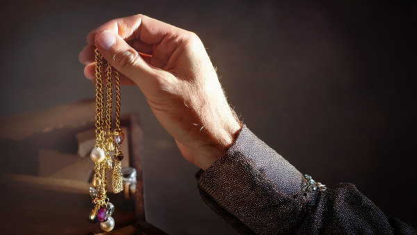 Sie sehen eine Hand die Schmuck nimmt.