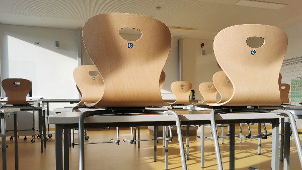 Sie sehen ein leeres Klassenzimmer mit Stühlen und Tischen.