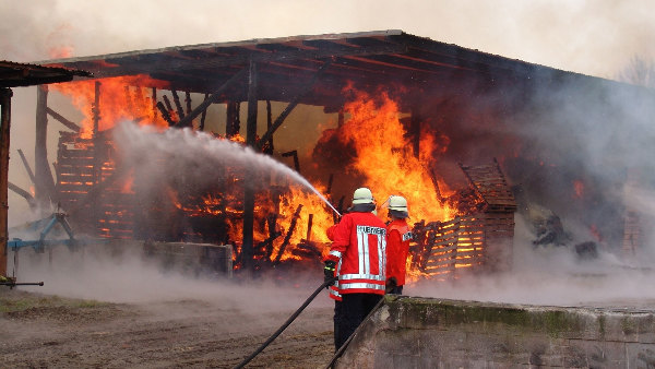 Sie sehen die Feuerwehr beim Löschen eines Lagerhausbrandes.