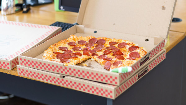 Sie sehen mehere Pizza-Kartons auf einem Tisch.