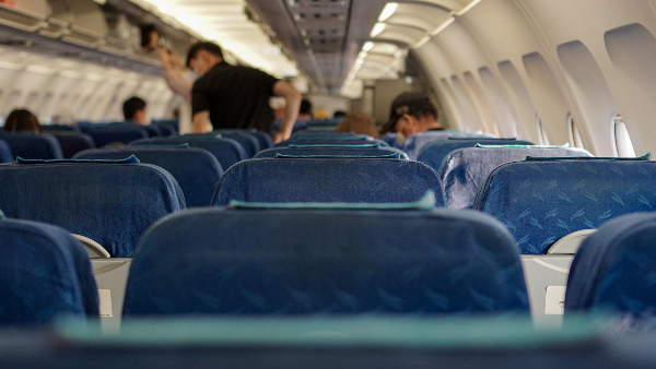 Sie sehen den Innenraum eines Linienflugzeugs und mehrere junge Männer darin.